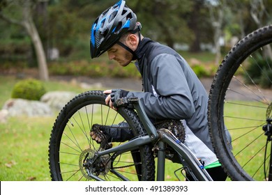 Male cyclist repairing his mountain bike in park