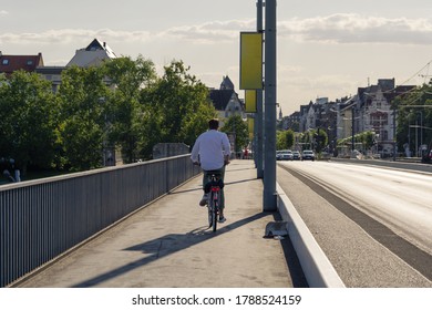 Male Cyclist Ride Bicycle On Bicycle Lane Beside Road On The Bridge Cross Rhine River In Düsseldorf, Germany. Cycling Friendly City Concept In Europe. 