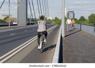 Male Cyclist Ride Bicycle On Bicycle Lane Beside Road On The Bridge Cross Rhine River In Düsseldorf, Germany. Cycling Friendly City Concept In Europe. 