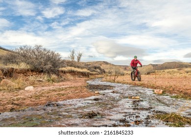 Male Cyclist Is Riding A Fat Mountain Bike Along A Stream In Red Mountain Open Space, Colorado , Late Fall Scenery