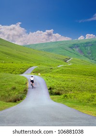 Male Cyclist Riding Up A Hill On A Road In Summer Portrait