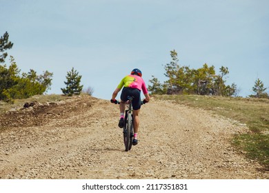 Male Cyclist Riding Uphill Trail On Mountain Bike