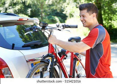 Male Cyclist Taking Mountain Bike From Rack On Car