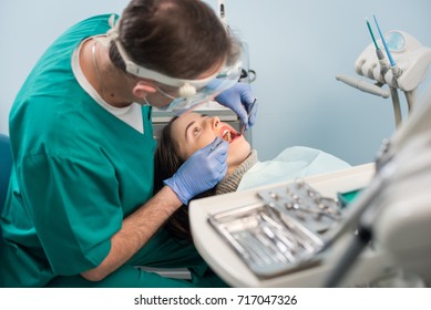 Male dentist with dental tools - mirror and probe checking up patient teeth at dental clinic office. Medicine, dentistry and health care concept. Dental equipment