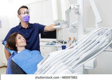 Male Dentist Explaining Xray To Female Patient In Clinic