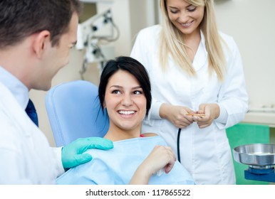 Male Dentist, His Assistant And Female Patient In Dental Practice