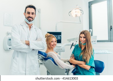 Male Dentist, His Assistant And Female Patient In Dental Practice