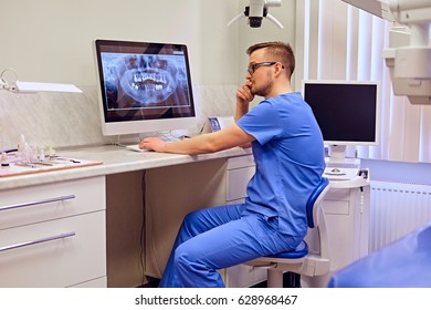 Male Dentist Looking At Teeth X-ray On The Computer In A Dentist Office.