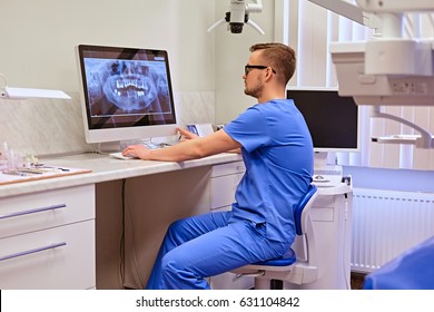 Male Dentist Looking At Teeth X-ray On The Computer In A Dentist Office.