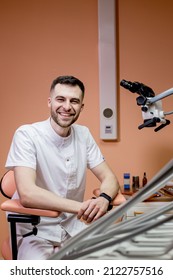 A Male Dentist Looks Into A Microscope. Modern Dentistry Using New Technologies.