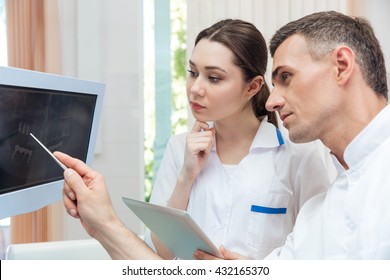 Male Dentist Showing Something On The Computer Monitor To Female Nurse At Clinic