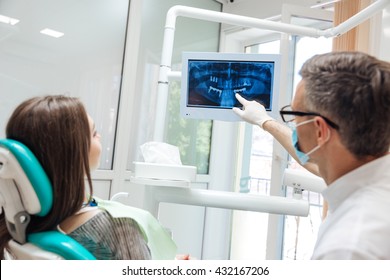 Male dentist shows a patient x-ray of teeth in clinic