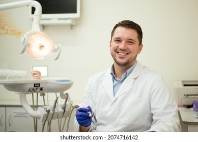 Male Dentist Smiling And Holding Tools In His Hands. High Quality Photo