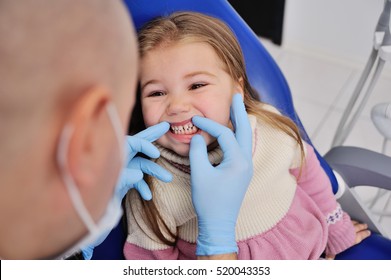 Male Dentist In Sterile Medical Mask Examining Baby Teeth