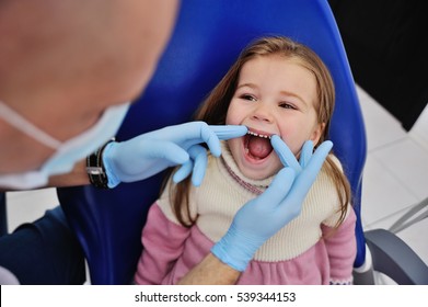 Male Dentist In Sterile Medical Mask Examining Baby Teeth