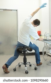 Male Dentist Stretching His Legs And Arms In The Office During Break