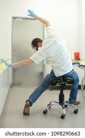 Male Dentist Stretching His Legs And Arms In The Office During Break