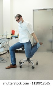 Male Dentist Stretching His Legs  In The Office During Break