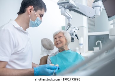 Male Dentist Talking To His Senipr Patient And Explaining Her Diagnosis