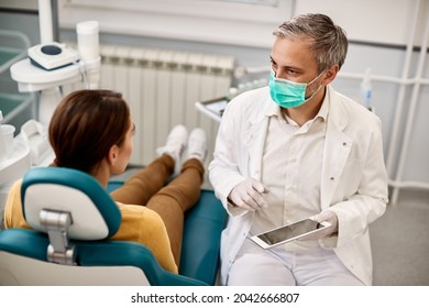 Male Dentist Using Digital Tablet And Talking To His Patient At Dental Clinic. 