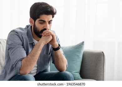 Male Depression. Upset Arab Man Having Problems, Sitting On Couch At Home And Thinking, Having Heavy Thoughts, Breake Up With Lover Or Financial Difficulties Concept, Empty Space