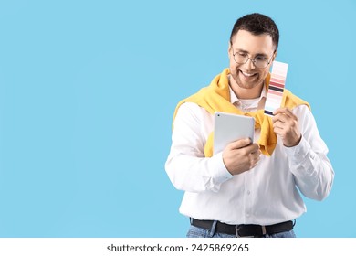 Male designer with paint color palette and tablet computer video chatting on blue background - Powered by Shutterstock