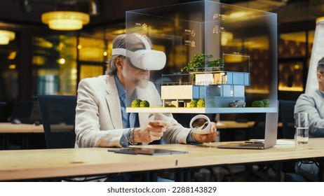 Male designer uses VR headset and wireless controllers, makes architectural project, creates house exterior design in virtual reality. Modern hi-tech company. 3D hologram. Future digital technologies. - Powered by Shutterstock