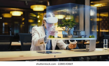 Male designer uses VR headset and wireless controllers, makes architectural project, creates house exterior design in virtual reality. Modern hi-tech company. 3D hologram. Future digital technologies. - Powered by Shutterstock