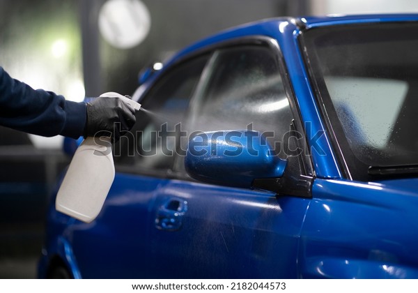 male detailer doing work on the car,\
cleaning machine and applying spray on the\
surface