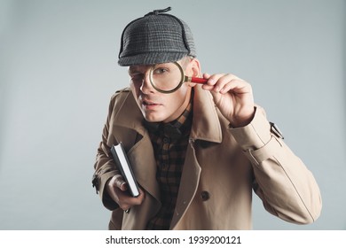 Male detective looking through magnifying glass on grey background - Shutterstock ID 1939200121