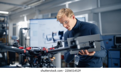 Male Developer Works On Engineering Project, Codes On Laptop And Looks At Drone In Modern Office. Empowered Person Creating Futuristic Unmanned Aerial Vehicles For Delivery Concept.