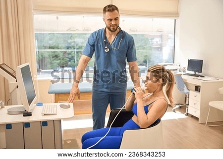Male dietologist watching woman taking resting metabolic rate test