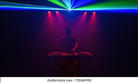 Male Disc jockey, DJ, silhouette with laser light. Front view