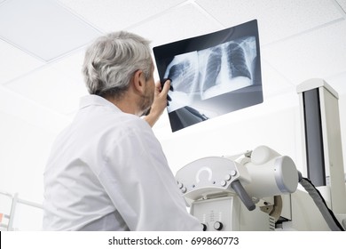 männlicher Arzt, der die BrustRöntgenaufnahme im Untersuchungsraum analysiert