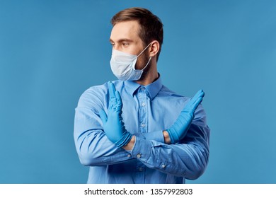 Male Doctor In Blue Gloves In Medical Mask On Blue Background