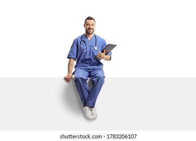 Male Doctor In A Blue Uniform Sitting On A Blank Panel Isolated On White Background