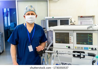 Male doctor in blue uniform wears medical mask in hands. Light background. Medical worker in office - Powered by Shutterstock