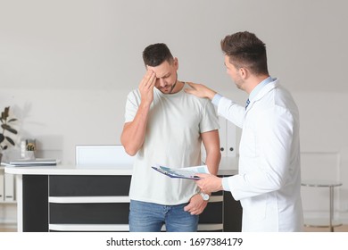 Male Doctor Calming Sad Patient In Clinic