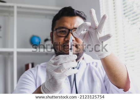 Male doctor checking and flicking a syringe, preparation before injecting