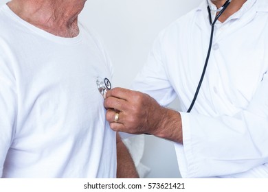 Male doctor checking heartbeat of senior man in the hospital - Shutterstock ID 573621421