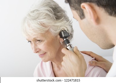 Male doctor checking patient's ear using otoscope - Powered by Shutterstock