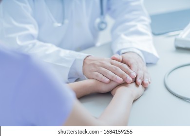 Male Doctor Comforting Patient At Consulting Room. Asian People