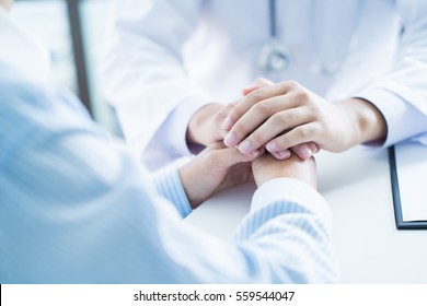 Male Doctor Comforting Patient At Consulting Room