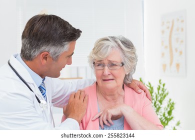 Male Doctor Consoling Senior Female Patient In Clinic