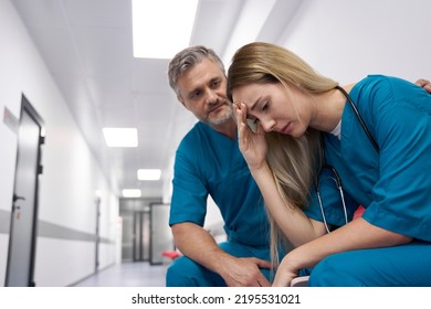 Male Doctor In Corridor Comforting Sad Female Doctor