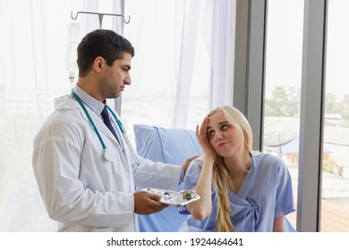 Male Doctor Examines The Symptoms Of A Woman's Patient In The Bed And Talks About His Illness At Hospital