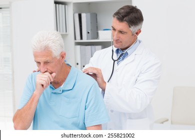 Male doctor examining coughing senior patient in clinic - Powered by Shutterstock