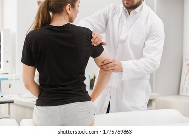 Male Doctor Examining Female Patient Suffering From Elbow Pain. Medical Exam. Chiropractic, Osteopathy, Post Traumatic Rehabilitation,sport Physical Therapy. Alternative Medicine, Pain Relief Concept.