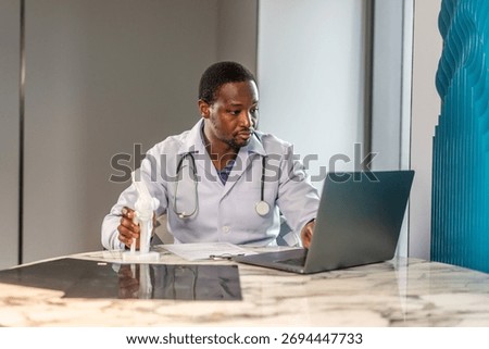 Male doctor is explaining something using an anatomical model bone while having online consultation with a patient, talking scoliosis, herniated discs, osteoporosis, diagnosing bone density issues
