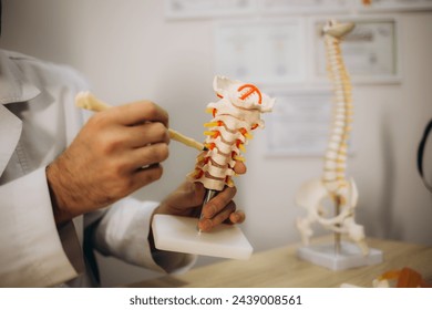 Male doctor explaining spinal anatomy with vertebral column model to patient in clinic. High quality photo - Powered by Shutterstock